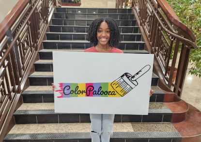 peyton phillips holding a sign of the ColorPalooza logo she designed